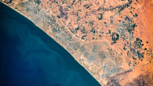 photo prise depuis l'espace montrant une ville côtière avec la mer et la terre